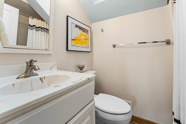 bathroom featuring vanity, toilet, and lofted ceiling