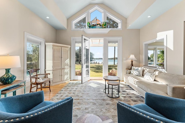 living room featuring a water view, light hardwood / wood-style flooring, and high vaulted ceiling