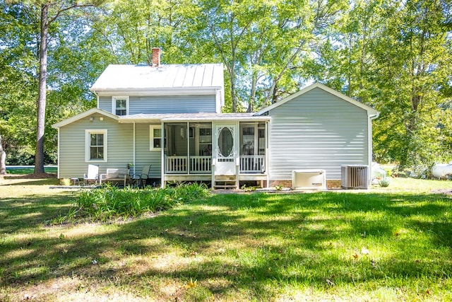 rear view of house with a sunroom, a yard, and central AC unit