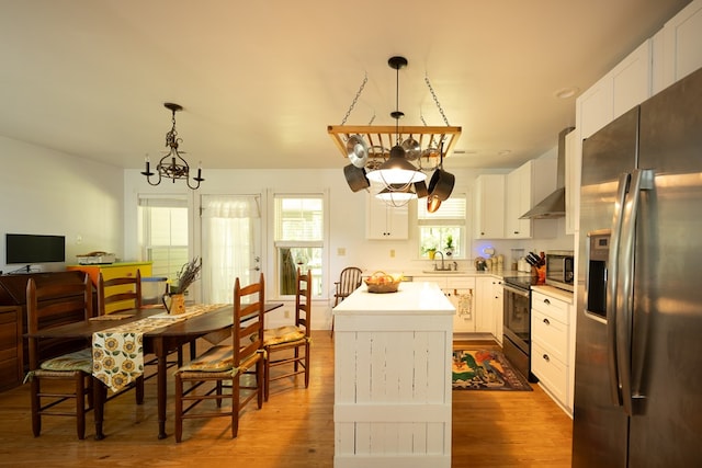 kitchen featuring appliances with stainless steel finishes, a kitchen island, an inviting chandelier, and pendant lighting