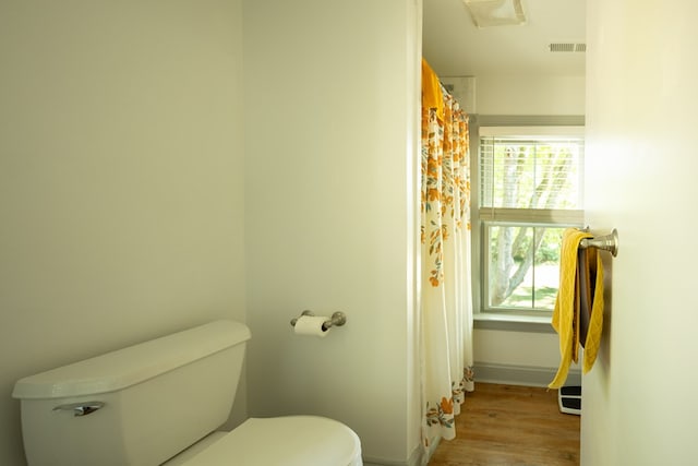 bathroom featuring a wealth of natural light, hardwood / wood-style flooring, and toilet