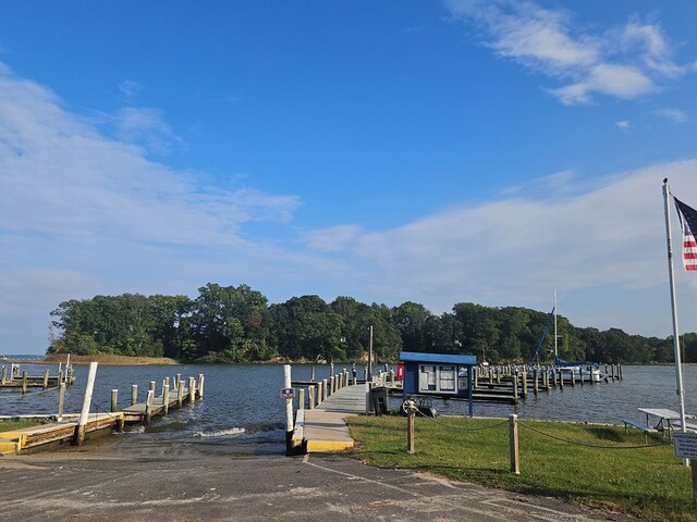 view of dock featuring a lawn and a water view
