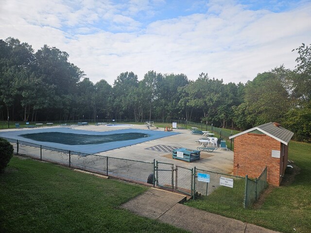 community pool featuring a lawn, fence, a gate, and a patio area