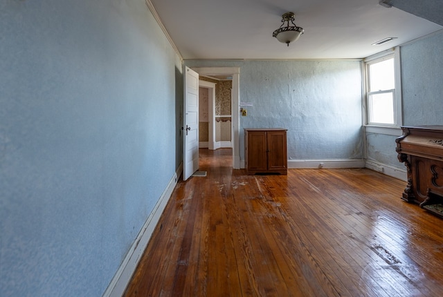 empty room with ornamental molding and dark hardwood / wood-style flooring