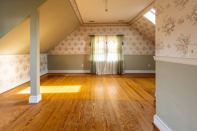 bonus room with vaulted ceiling with skylight, hardwood / wood-style floors, and baseboard heating