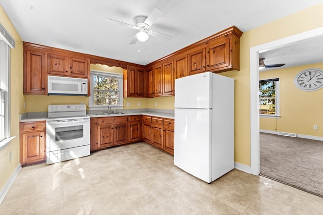 kitchen featuring ceiling fan, sink, white appliances, and light carpet