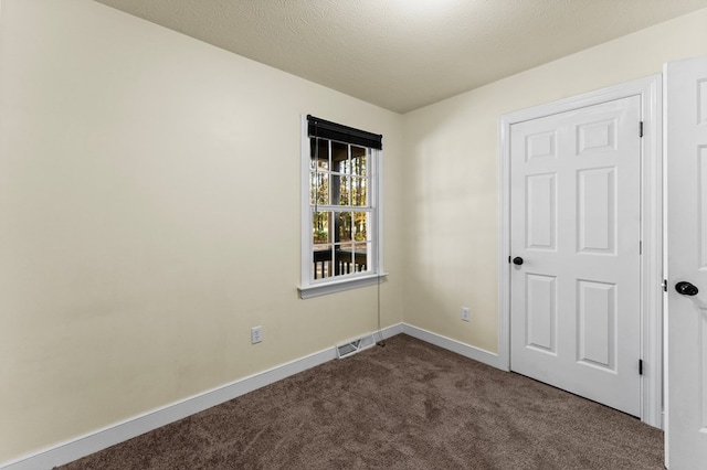 unfurnished room with carpet flooring and a textured ceiling