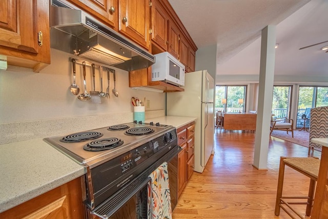 181 Cross St, Urbanna, VA 23175 - kitchen featuring white appliances, under cabinet range hood, brown cabinets, light wood finished floors, and plenty of natural light