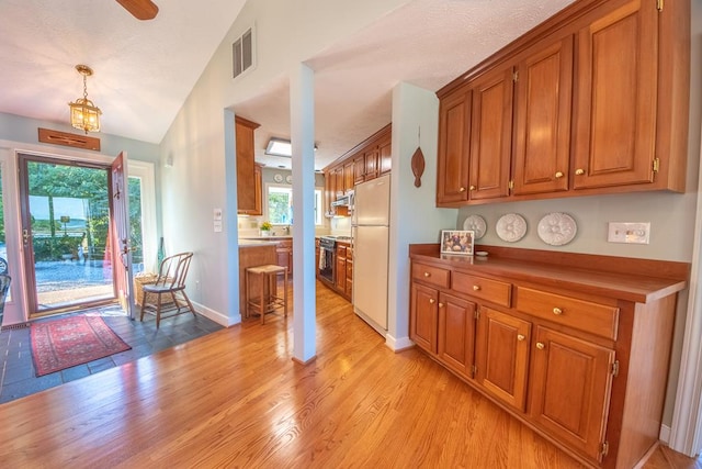 181 Cross St, Urbanna, VA 23175 - kitchen featuring brown cabinets, freestanding refrigerator, light wood finished floors, and vaulted ceiling
