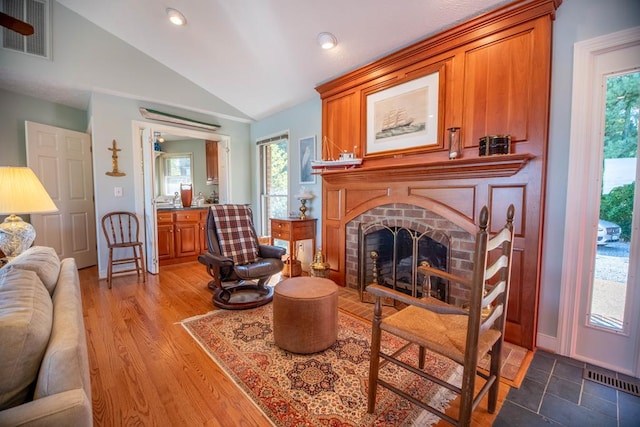 181 Cross St, Urbanna, VA 23175 - living area with vaulted ceiling, plenty of natural light, a brick fireplace, wood finished floors, and recessed lighting
