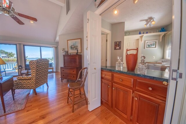 181 Cross St, Urbanna, VA 23175 - kitchen featuring light wood-type flooring, ceiling fan, brown cabinets, lofted ceiling, and dark stone countertops
