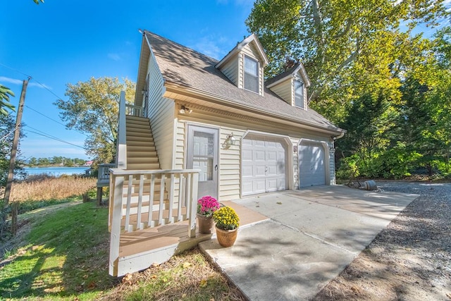 181 Cross St, Urbanna, VA 23175 - view of home's exterior with stairs, driveway, a garage, a shingled roof, and a lawn
