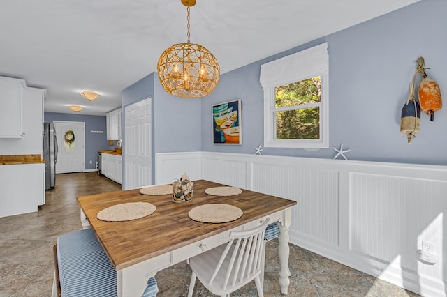 1198 Knights Landing Dr, Heathsville, VA 22473 - dining area with stone finish flooring, a wainscoted wall, a chandelier, and a decorative wall