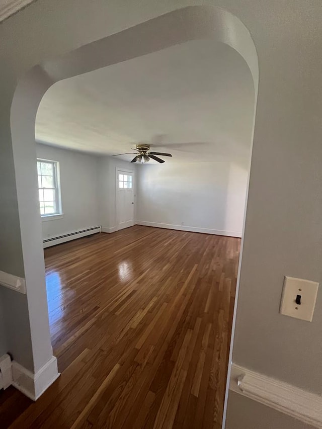 unfurnished room featuring baseboard heating, ceiling fan, and dark hardwood / wood-style flooring