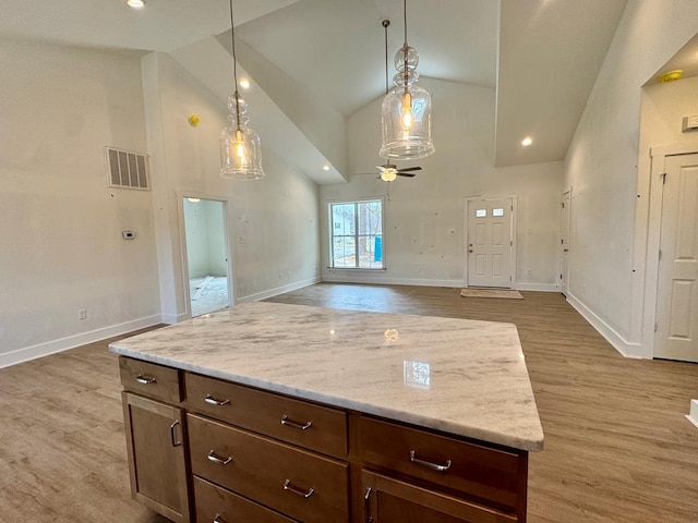 kitchen featuring visible vents, baseboards, wood finished floors, hanging light fixtures, and high vaulted ceiling