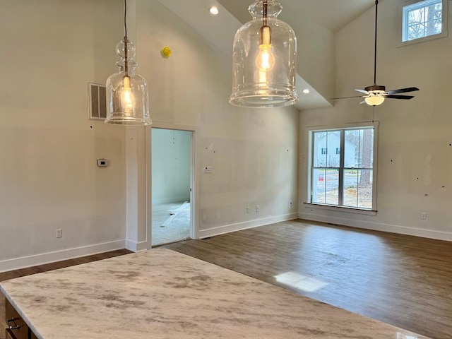 unfurnished dining area with dark wood finished floors, high vaulted ceiling, and baseboards