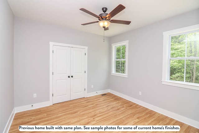 unfurnished bedroom with multiple windows, ceiling fan, a closet, and hardwood / wood-style flooring