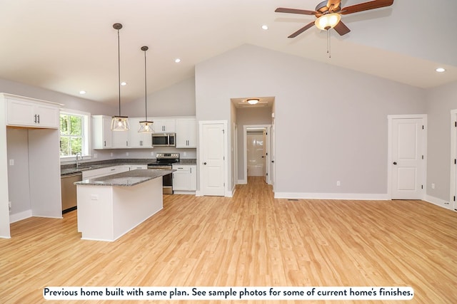 kitchen with white cabinets, a kitchen island, stainless steel appliances, and hanging light fixtures