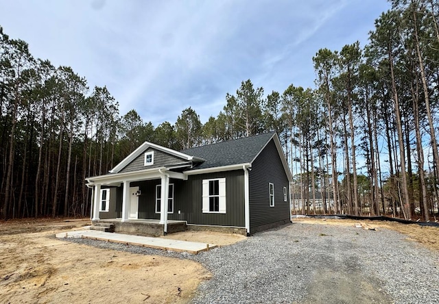 view of front facade featuring a porch, a shingled roof, and driveway