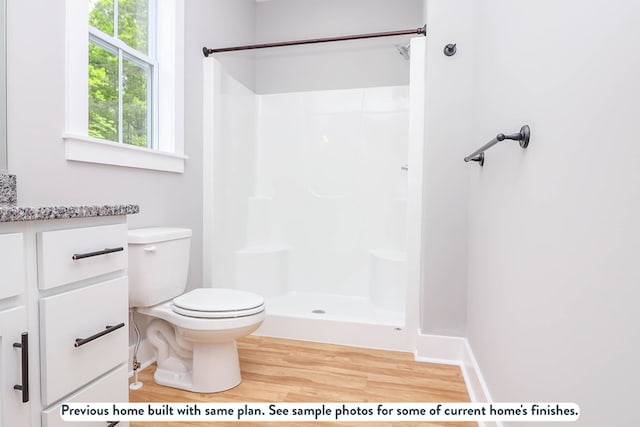 bathroom featuring hardwood / wood-style floors, vanity, toilet, and walk in shower