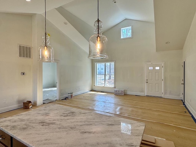 interior space with light wood-type flooring, baseboards, visible vents, and high vaulted ceiling