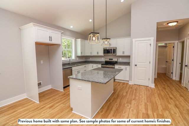 kitchen with stainless steel appliances, sink, white cabinets, a center island, and hanging light fixtures