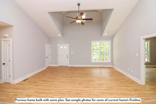 unfurnished living room with ceiling fan, high vaulted ceiling, and light hardwood / wood-style flooring