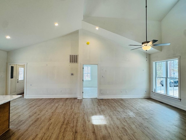 unfurnished living room featuring baseboards, high vaulted ceiling, a healthy amount of sunlight, and wood finished floors