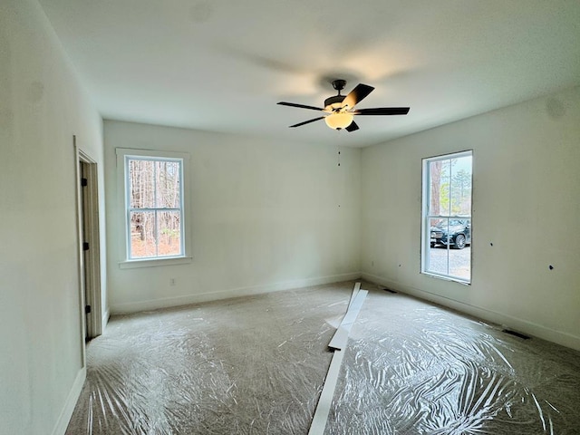 empty room featuring visible vents, ceiling fan, and baseboards