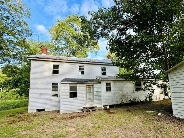 back of property with solar panels and a yard