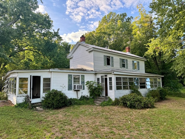 rear view of house with a lawn, a sunroom, and cooling unit