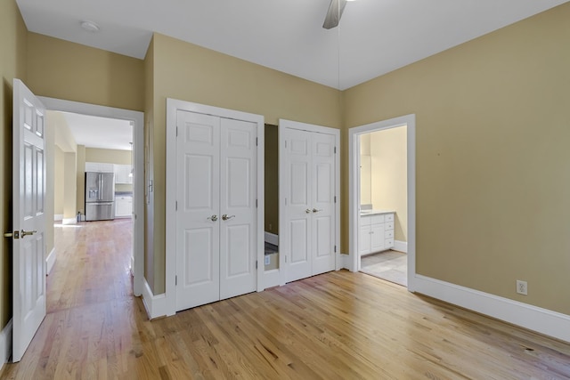 unfurnished bedroom featuring connected bathroom, stainless steel fridge with ice dispenser, two closets, and light hardwood / wood-style flooring