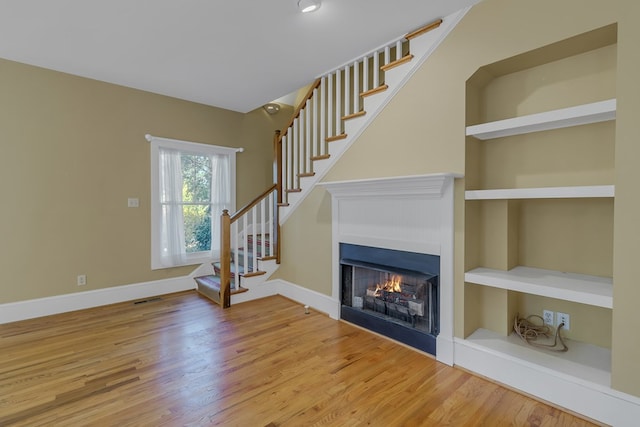 unfurnished living room with hardwood / wood-style flooring and built in features