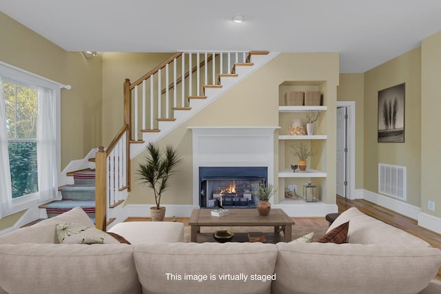 living room with built in shelves and wood-type flooring