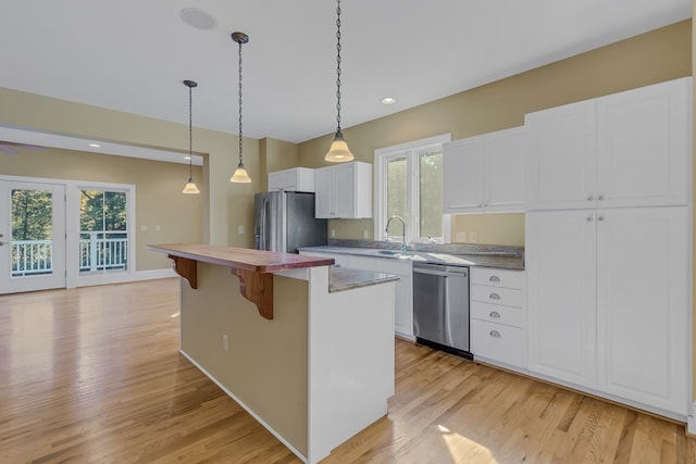 kitchen with sink, white cabinetry, a kitchen breakfast bar, a kitchen island, and stainless steel appliances