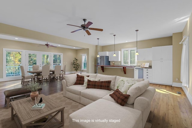 living room with ceiling fan, sink, light hardwood / wood-style floors, and french doors