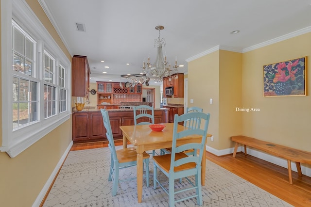 dining area featuring an inviting chandelier, light hardwood / wood-style flooring, and ornamental molding