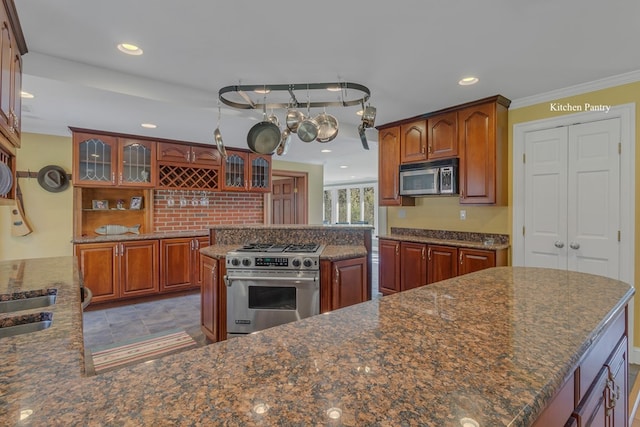 kitchen with dark stone counters, crown molding, a kitchen island, and stainless steel appliances