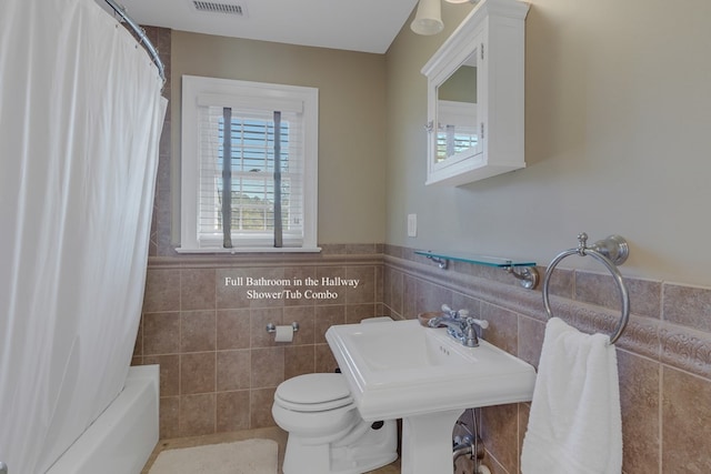 bathroom featuring toilet, tile walls, and shower / tub combo