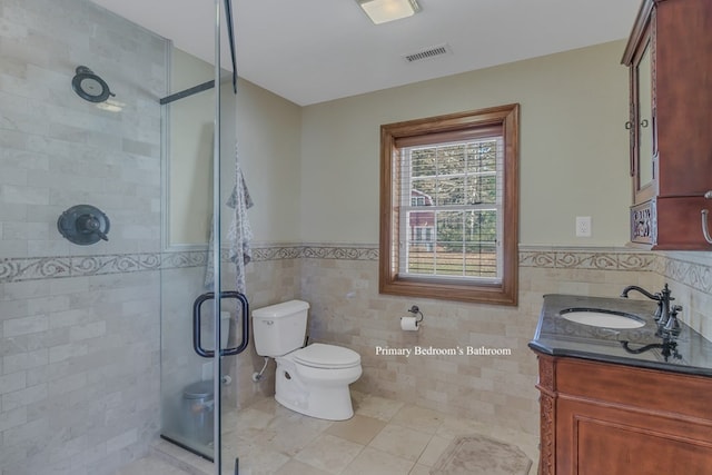 bathroom with tile patterned flooring, vanity, a shower with door, and tile walls