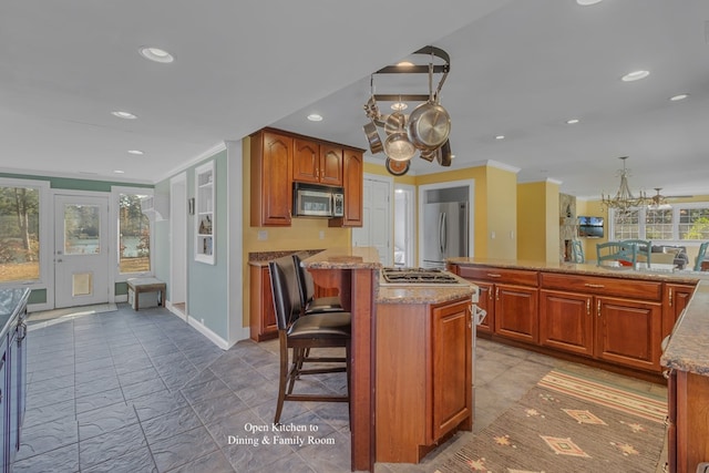 kitchen with a center island, a notable chandelier, crown molding, a breakfast bar, and appliances with stainless steel finishes