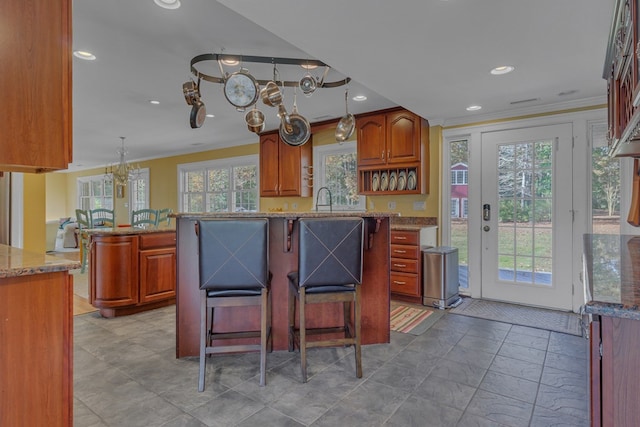 kitchen with decorative light fixtures, a center island, a healthy amount of sunlight, and ornamental molding