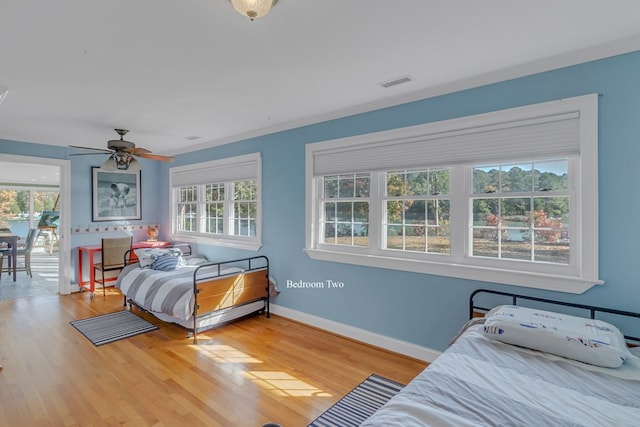 bedroom with multiple windows, ceiling fan, wood-type flooring, and ornamental molding