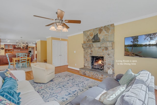 living room featuring light hardwood / wood-style floors, a stone fireplace, ceiling fan, and ornamental molding