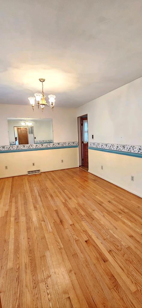 spare room featuring light hardwood / wood-style floors and a notable chandelier