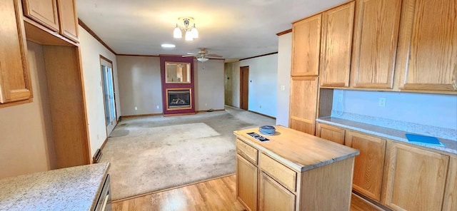 kitchen featuring crown molding, ceiling fan, light wood-type flooring, light stone countertops, and a kitchen island