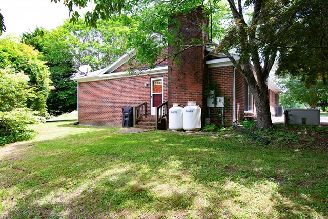 203 Lampkintown Rd, Burgess, VA 22432 - view of side of home with brick siding, a lawn, and central AC