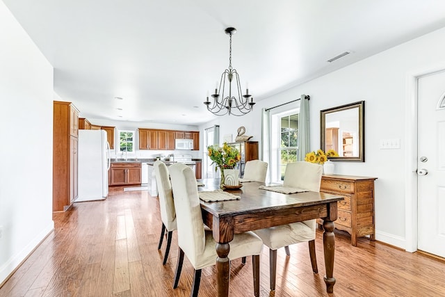 dining space with a wealth of natural light, a notable chandelier, and light wood finished floors