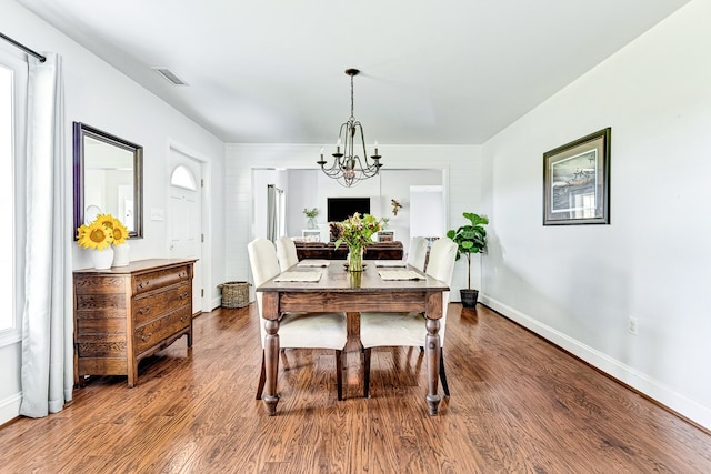 dining area featuring a chandelier, visible vents, baseboards, and wood finished floors