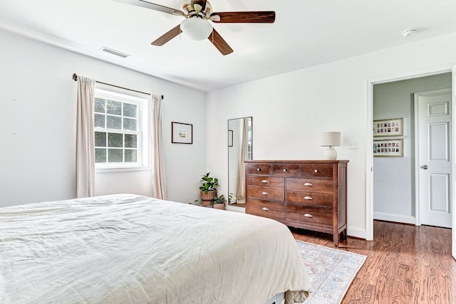 bedroom with visible vents, baseboards, wood finished floors, and a ceiling fan